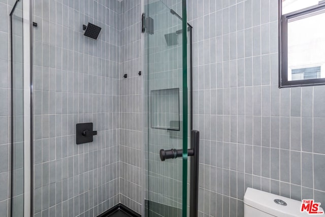 bathroom with a shower with shower door and toilet