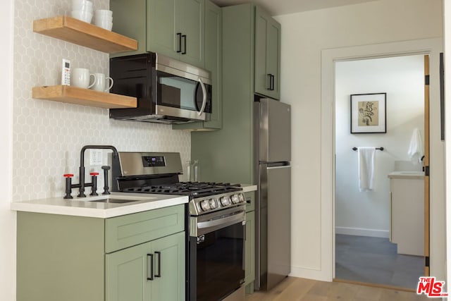 kitchen with sink, decorative backsplash, stainless steel appliances, and green cabinets