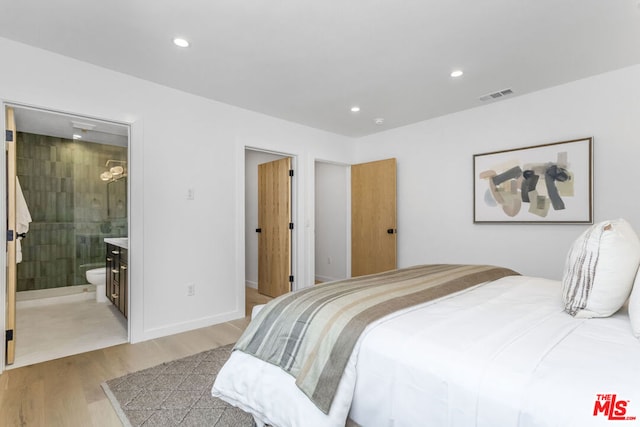 bedroom featuring ensuite bathroom and light hardwood / wood-style flooring