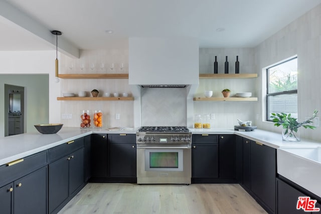 kitchen with stainless steel stove, hanging light fixtures, backsplash, kitchen peninsula, and light wood-type flooring