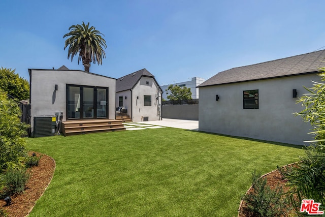 rear view of property featuring central AC unit, a patio, and a lawn