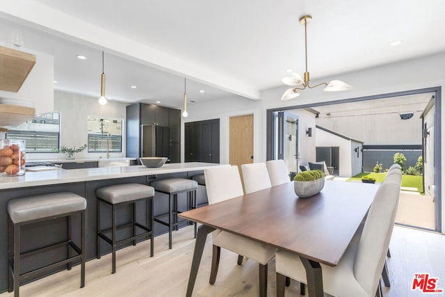 dining area featuring a chandelier, beam ceiling, and light hardwood / wood-style flooring