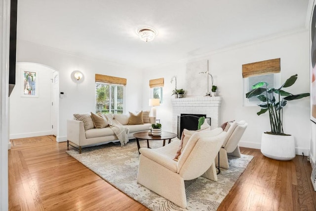 living room with crown molding, a brick fireplace, and hardwood / wood-style floors