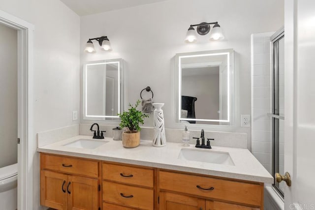 bathroom with vanity, a shower with shower door, and toilet