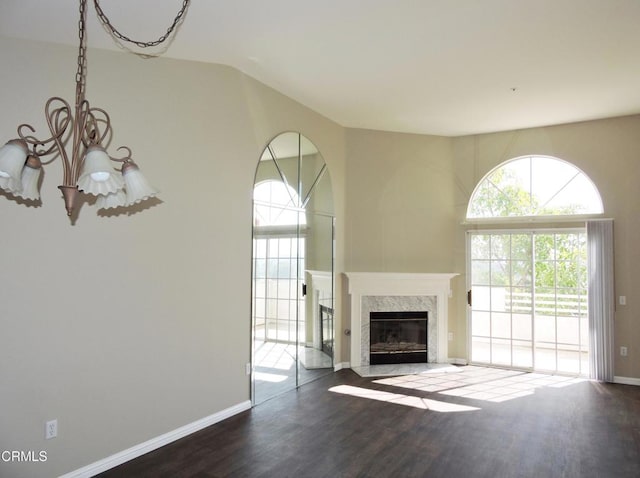 unfurnished living room with a fireplace, dark hardwood / wood-style flooring, high vaulted ceiling, and a notable chandelier