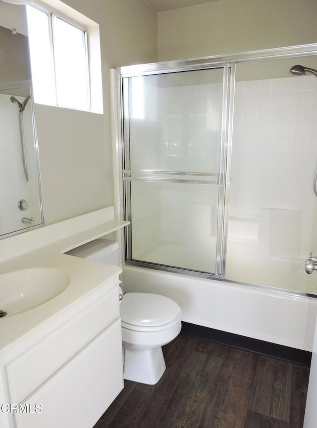 full bathroom featuring wood-type flooring, vanity, shower / bath combination with glass door, and toilet