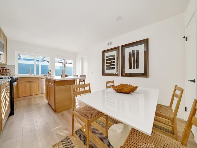 dining area with a water view, sink, and light wood-type flooring