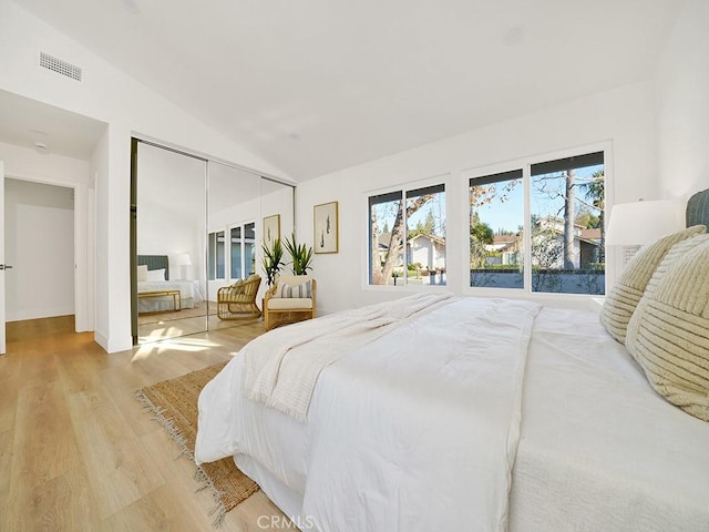 bedroom with a closet, lofted ceiling, and light hardwood / wood-style flooring