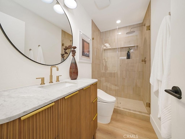 bathroom with hardwood / wood-style flooring, vanity, a shower with shower door, and toilet