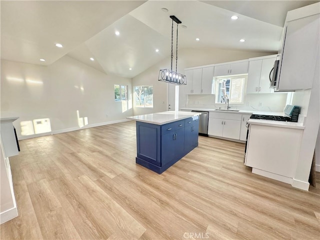 kitchen featuring blue cabinetry, appliances with stainless steel finishes, a kitchen island, pendant lighting, and white cabinets