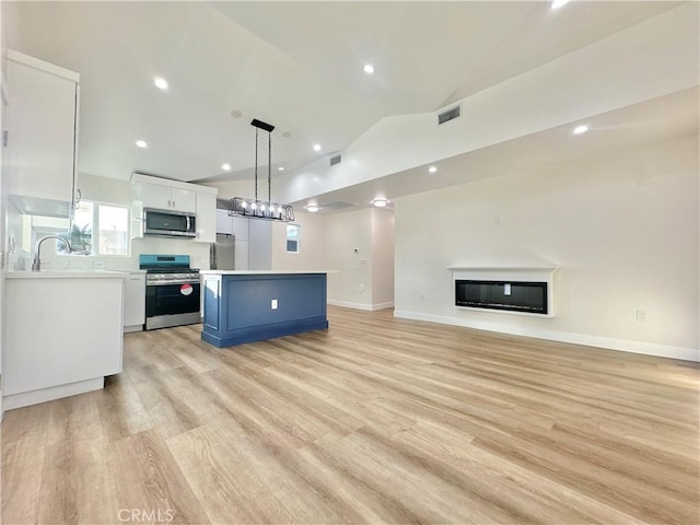 kitchen with blue cabinets, hanging light fixtures, a kitchen island, stainless steel appliances, and white cabinets