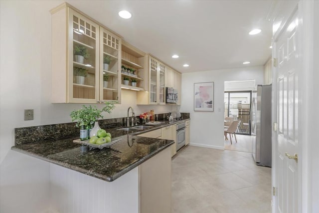 kitchen with stainless steel appliances, sink, dark stone countertops, and kitchen peninsula