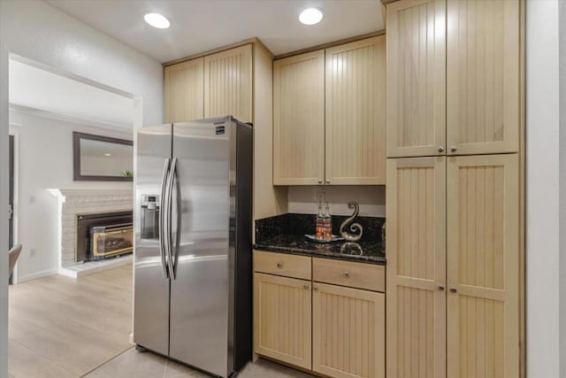 kitchen with dark stone countertops, light brown cabinetry, and stainless steel fridge with ice dispenser