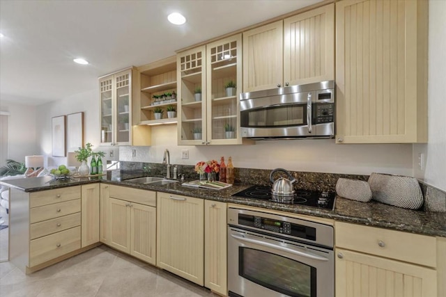 kitchen with stainless steel appliances, sink, dark stone countertops, and kitchen peninsula