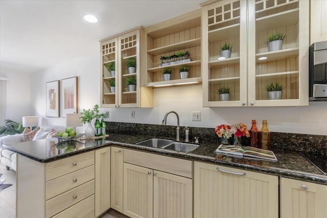 kitchen with kitchen peninsula, sink, and dark stone countertops