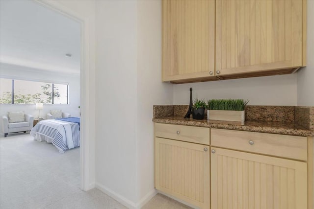 interior space featuring dark stone countertops, light colored carpet, and light brown cabinets