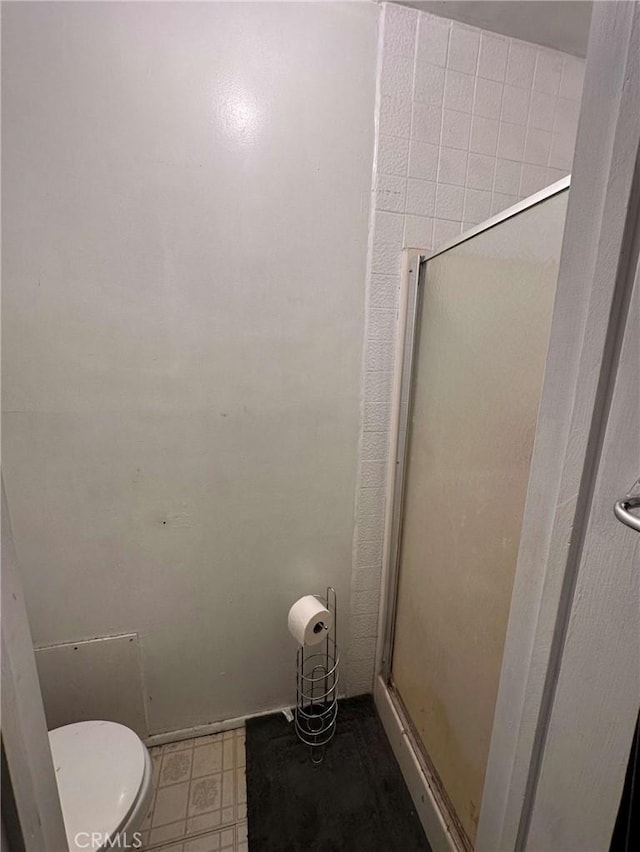 bathroom with toilet and a shower with shower door