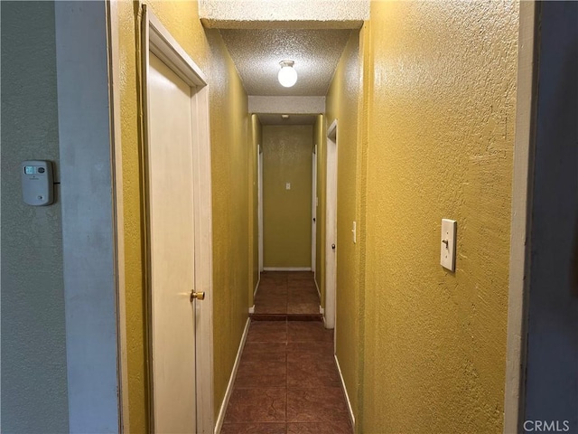 corridor featuring dark tile patterned flooring and a textured ceiling