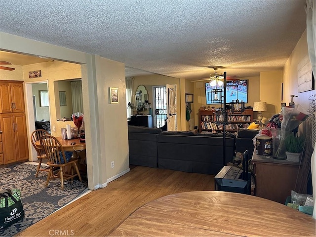 living room with ceiling fan, light hardwood / wood-style floors, and a textured ceiling