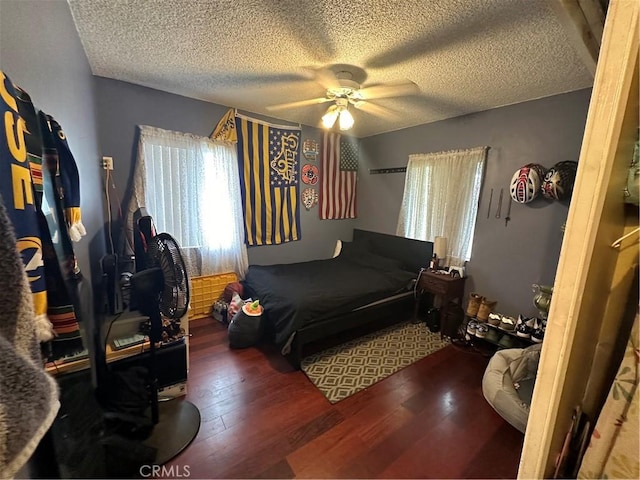 bedroom featuring ceiling fan, a textured ceiling, and dark hardwood / wood-style flooring