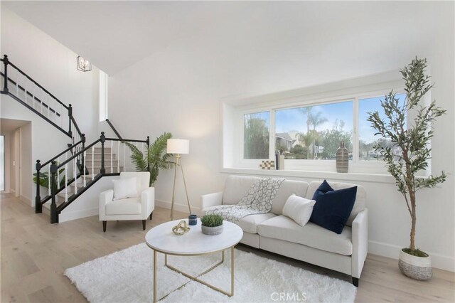 living area with stairs, wood finished floors, lofted ceiling, and baseboards