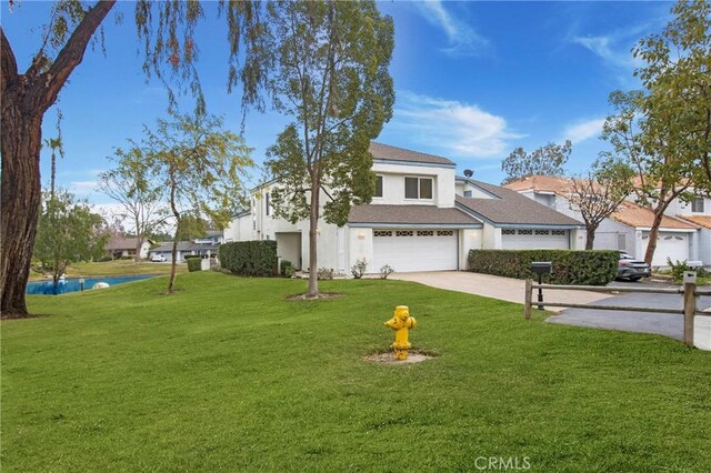 view of front of house featuring an attached garage, driveway, a front yard, and stucco siding