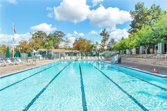 community pool with a patio and fence