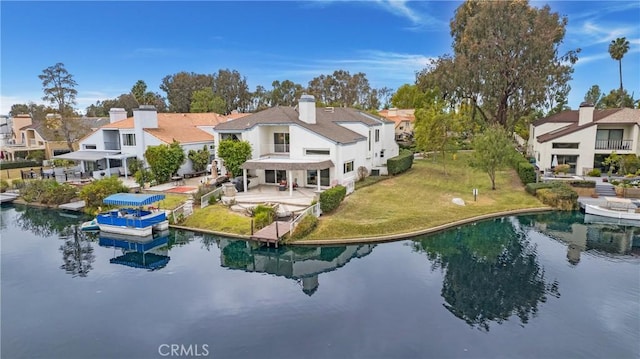 back of property featuring a yard, a patio area, and a water view