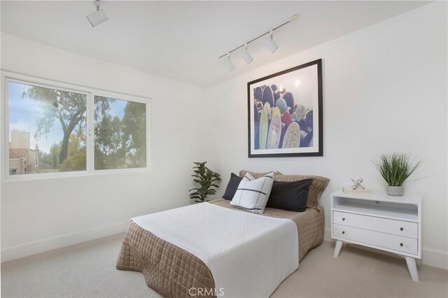 carpeted bedroom featuring track lighting