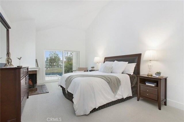 bedroom featuring access to exterior, carpet flooring, high vaulted ceiling, and a lit fireplace