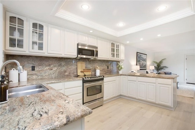 kitchen with stainless steel appliances, sink, white cabinets, and a tray ceiling