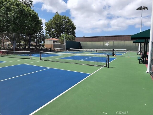 view of tennis court with community basketball court and fence