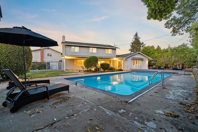 pool at dusk featuring a patio area