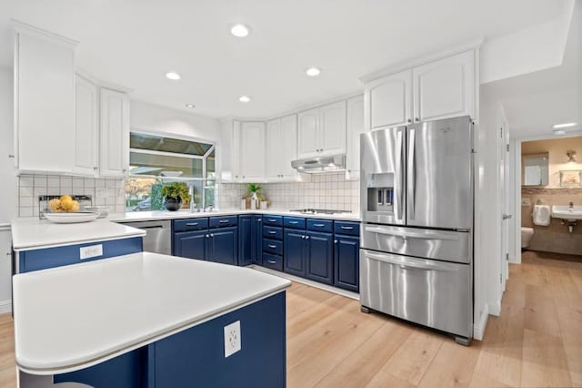 kitchen with appliances with stainless steel finishes, blue cabinets, light hardwood / wood-style flooring, and white cabinets