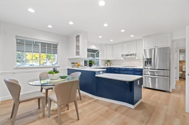 kitchen with blue cabinets, stainless steel fridge with ice dispenser, light hardwood / wood-style flooring, white cabinets, and backsplash