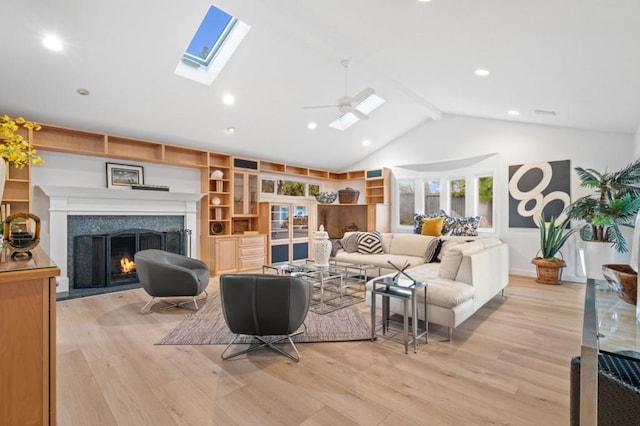 living room with beamed ceiling, a premium fireplace, light hardwood / wood-style floors, and a skylight