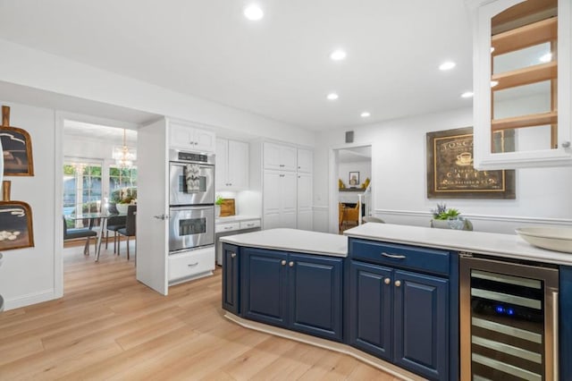 kitchen featuring wine cooler, white cabinetry, blue cabinetry, and stainless steel double oven