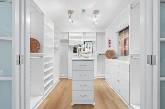 walk in closet with light hardwood / wood-style flooring