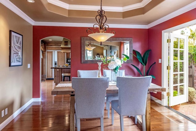 dining space featuring crown molding, hardwood / wood-style floors, and a tray ceiling