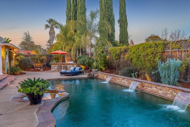 pool at dusk with a patio and pool water feature