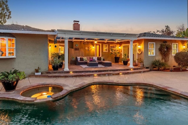 back house at dusk with an outdoor living space, a patio, and a swimming pool with hot tub