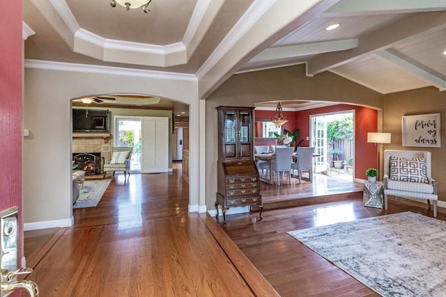 entryway featuring crown molding, dark hardwood / wood-style floors, a tile fireplace, and vaulted ceiling with beams