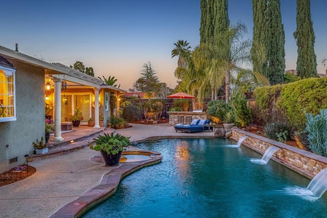 pool at dusk featuring pool water feature and a patio