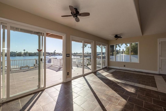 unfurnished sunroom with a water view and ceiling fan