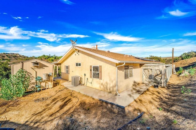 rear view of property with central AC, a storage shed, and a patio