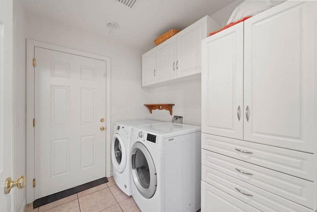 laundry room with independent washer and dryer, cabinets, and light tile patterned flooring