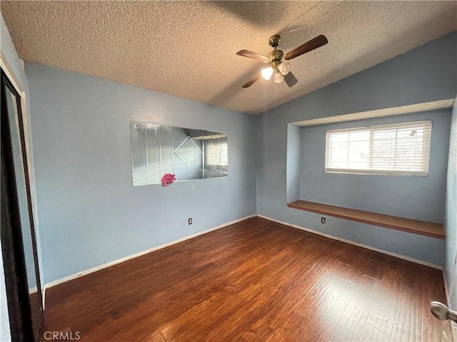 unfurnished room featuring ceiling fan, dark hardwood / wood-style floors, vaulted ceiling, and a textured ceiling