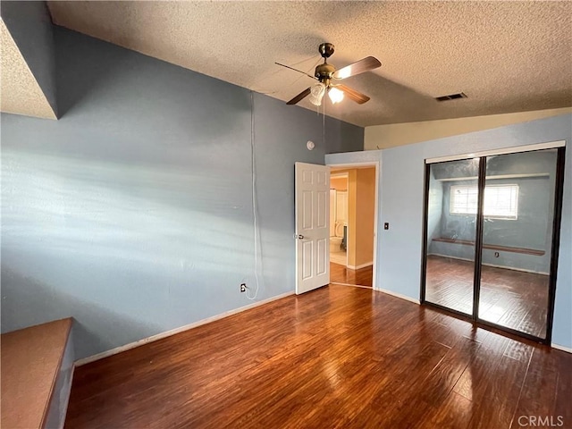 unfurnished bedroom featuring dark wood-type flooring, a closet, lofted ceiling, and a textured ceiling