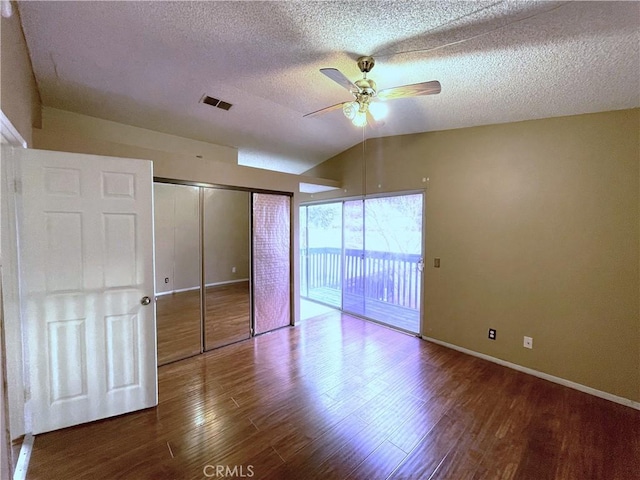 unfurnished bedroom featuring lofted ceiling, hardwood / wood-style flooring, access to outside, ceiling fan, and a closet