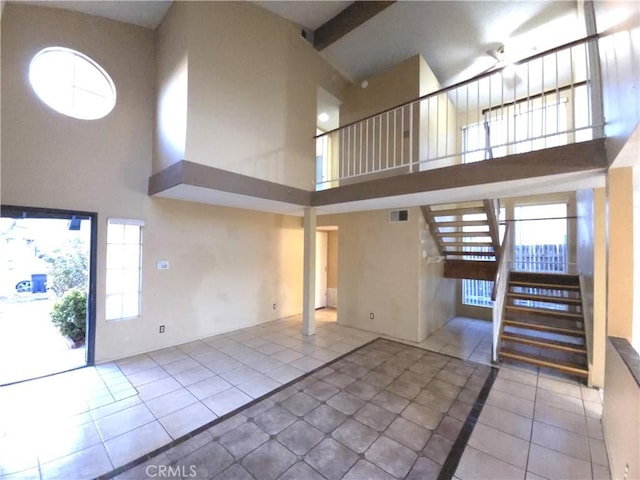 unfurnished living room featuring a towering ceiling and tile patterned floors